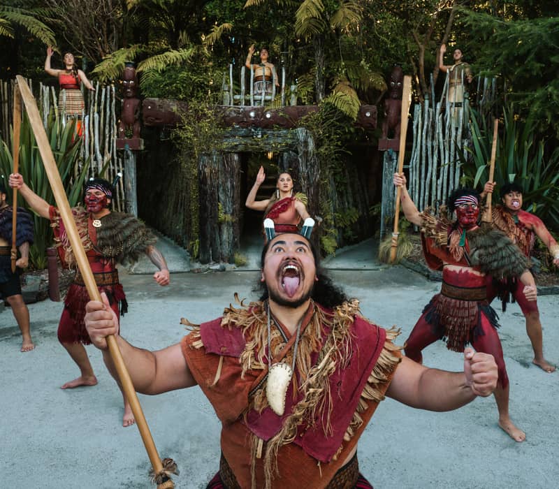 Maori kapa haka group performing traditional dance with spears and face paint in forest setting. Credit: Te Pa Tu