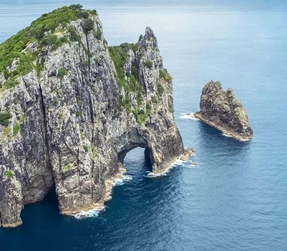 Hole in the Rock, Bay of Islands, New Zealand surrounded by blue sea.