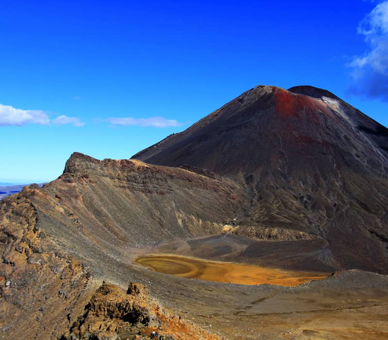 Mt Ngauruhoe volcano with orange crater lake under a clear blue sky Credit: New Zealand Fine Touring