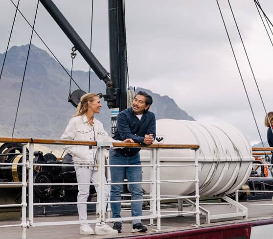Travelers on TSS Earnslaw steamboat with mountains.