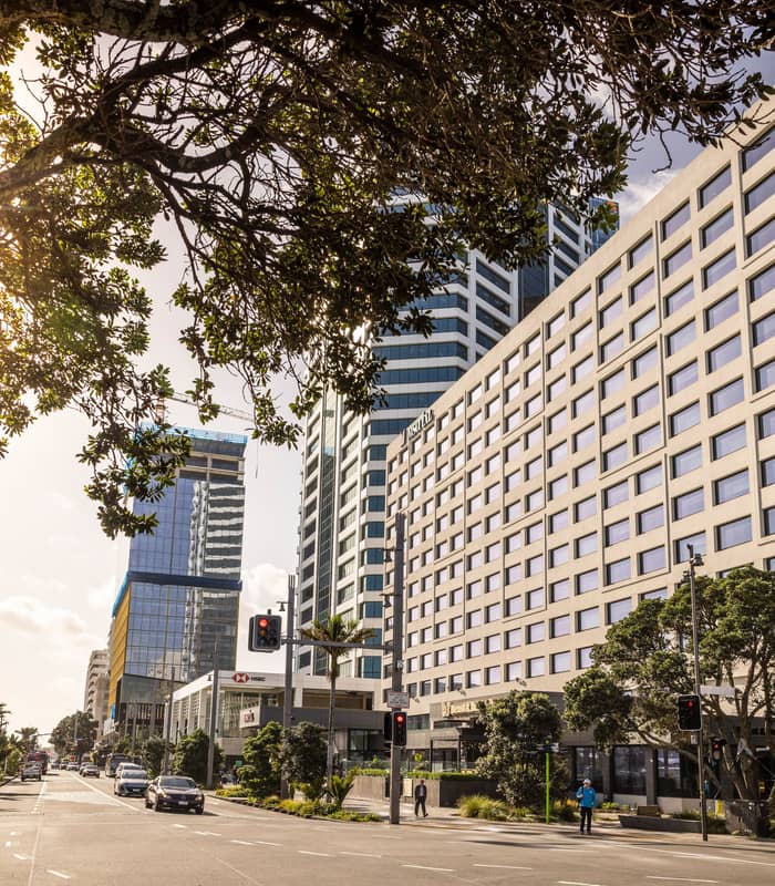 M Social Hotel Auckland building on a sunny day with street, cars, and trees in front. Credit: M Social Hotel Auckland