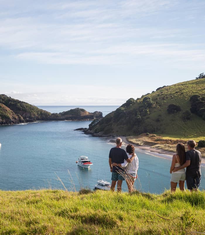 Couples overlooking a calm bay with boats and green hills in the Bay of Islands.