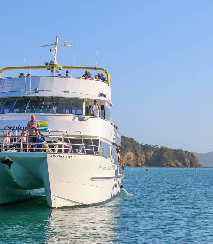 Tour boat cruising through the Bay of Islands with passengers onboard.
