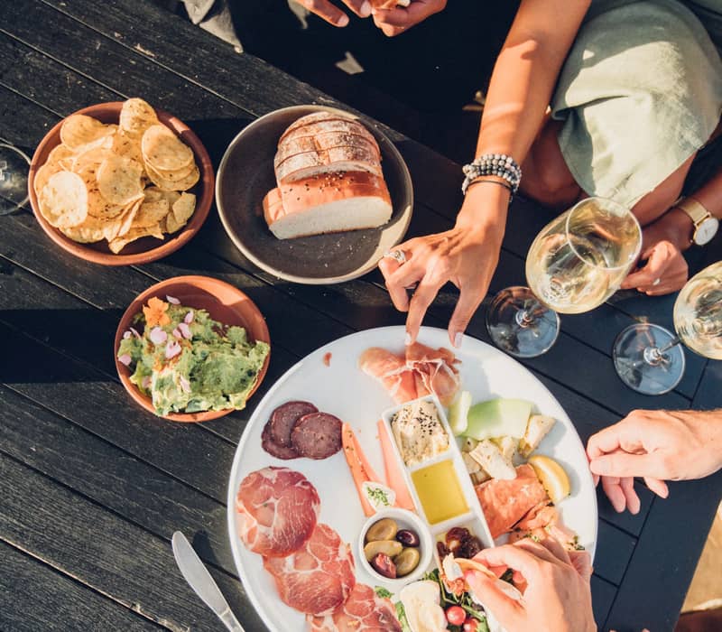 Friends sharing a charcuterie platter and wine at Stoney Ridge Vineyard.