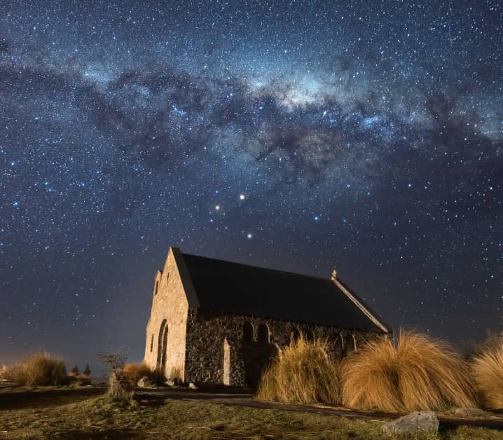 Milky Way starry night sky above a stone church and grassy landscape. Credit: G Adventures