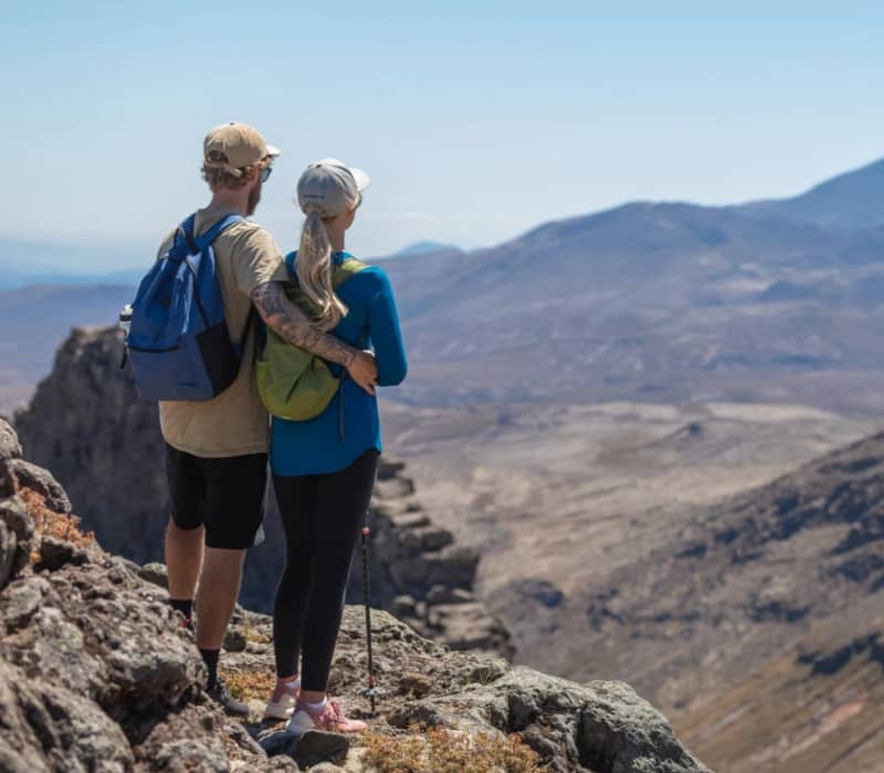 Couple standing on rocky terrain overlooking volcanic mountains during a hike. Credit: Great Journeys
