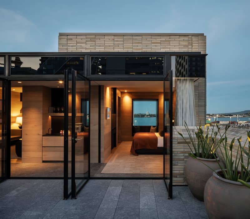 Luxury rooftop hotel suite in Auckland with an open terrace, harbor views, and modern timber-clad interiors. Credit: Hotel Britomart
